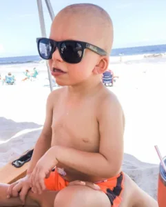 A kid sitting on beach in shades