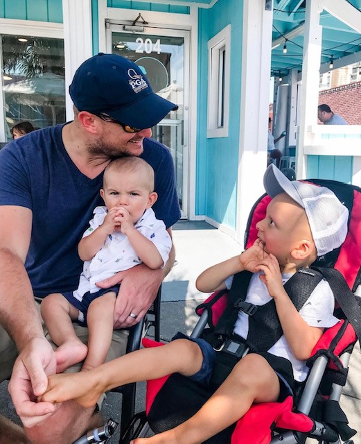 Brian Berry is holding his young son while stooping down to talk to his other son Nolan, who sits in the stroller next to him. 