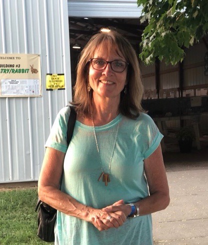 Nurse Gerayne Yelkin is pictured smiling. She wears glasses and has her hands clasped together in front of her. 