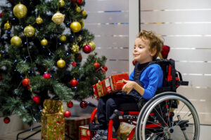 Child in wheelchair beside Christmas tree