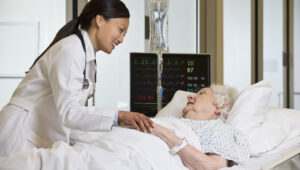 Doctor at older female patient's hospital bedside