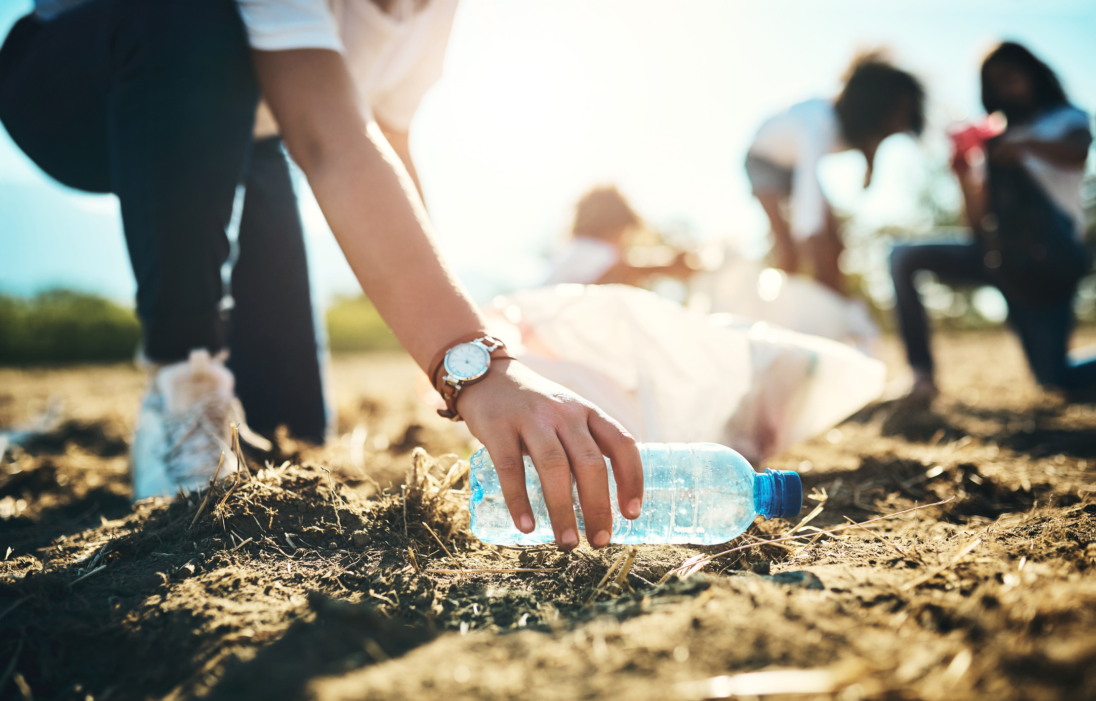 teenager picking up litter off of a field