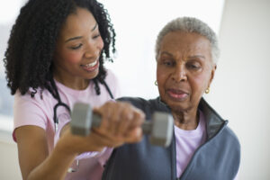 Nurse helping woman exercise with dumbbell