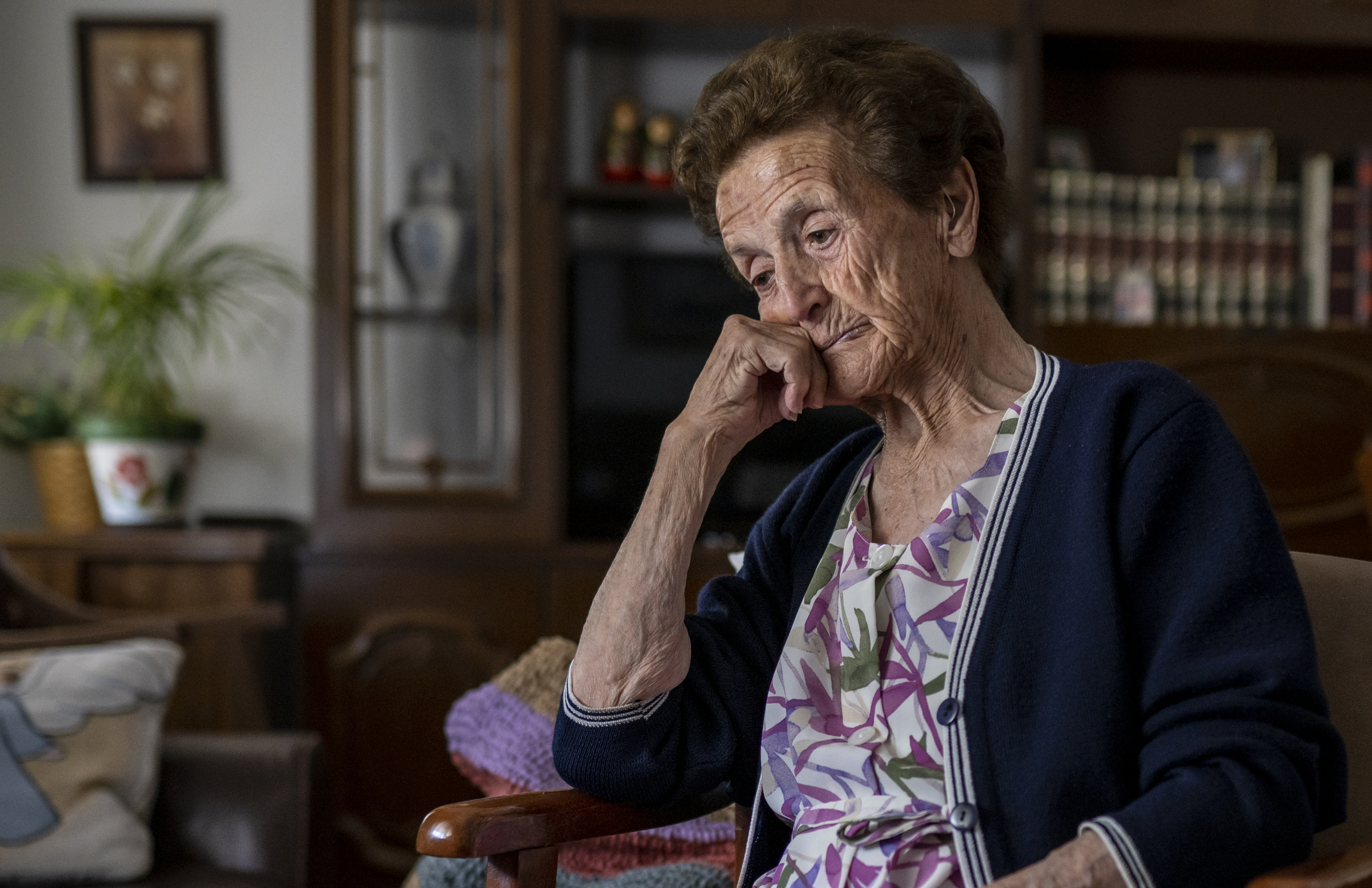 Senior woman sitting on sofa alone upset