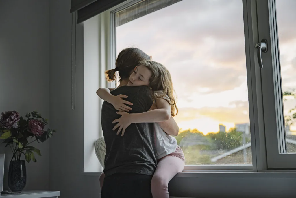 Woman hugging little girl tightly.