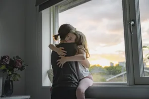 Woman hugging little girl tightly.