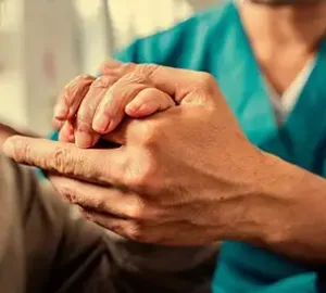 caregiver assisting an elderly man to get up from bed, providing supportive care in a home setting