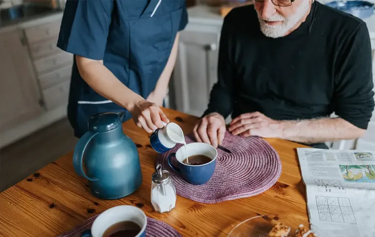 Caregiver assisting an elderly person with daily living tasks, symbolizing Maxim Healthcare's in-home supportive services.