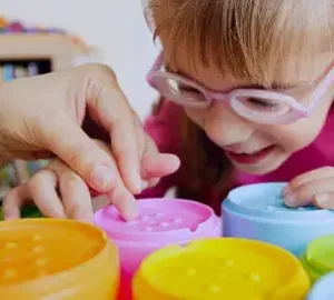 Young girl with glasses enjoying a colorful sensory activity, engaging with vibrant play materials.
