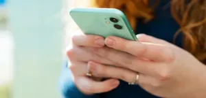 Close-up of woman using smartphone to access Maxim Healthcare patient services online
