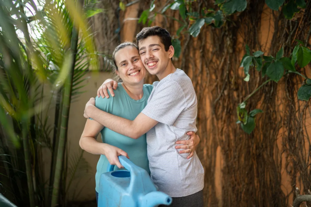 Woman and teenage boy embracing and smiling.