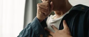 Photo of a man coughing and holding his chest.